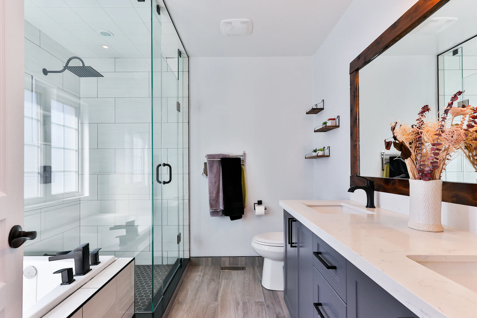 Remodeled bathroom with frameless glass shower, white tile, and a dark wood vanity