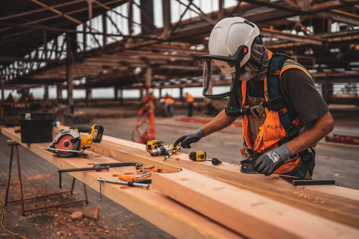 Carpenter in protective gear cutting lumber on a workbench